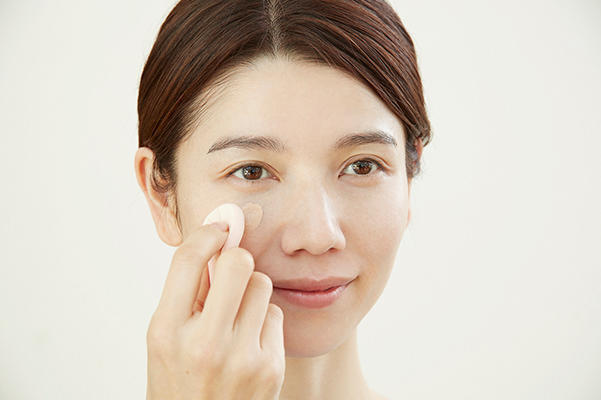 水スポンジでファンデーションを塗っている女性画像